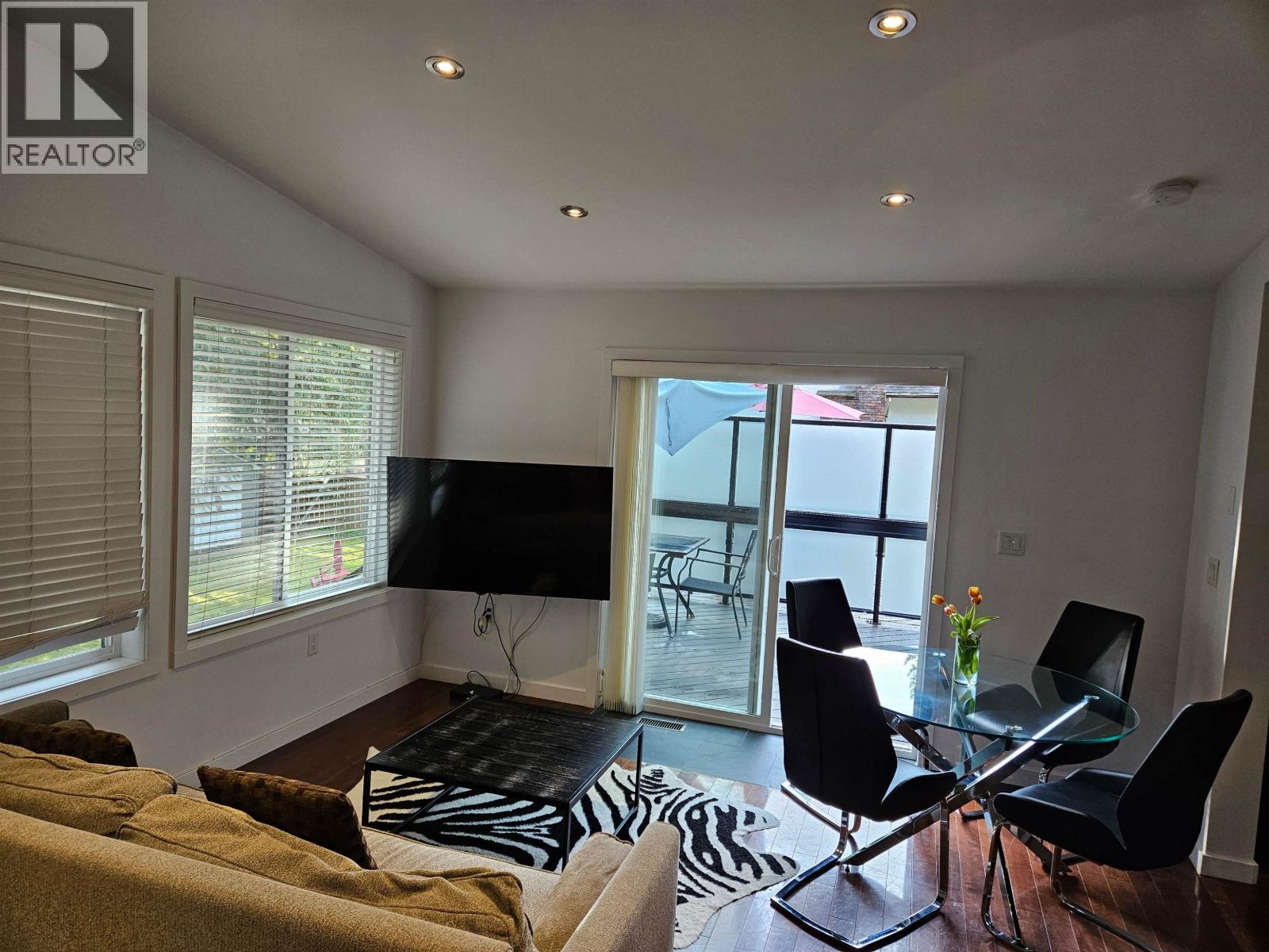 A living room with a glass dining table and chairs.