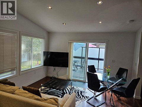 A living room with a glass dining table and chairs.