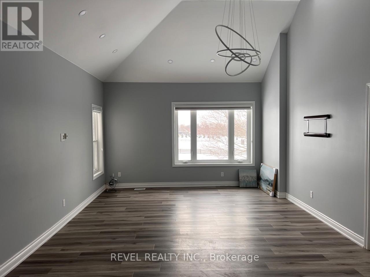 A spacious room with wooden floors and a large window.