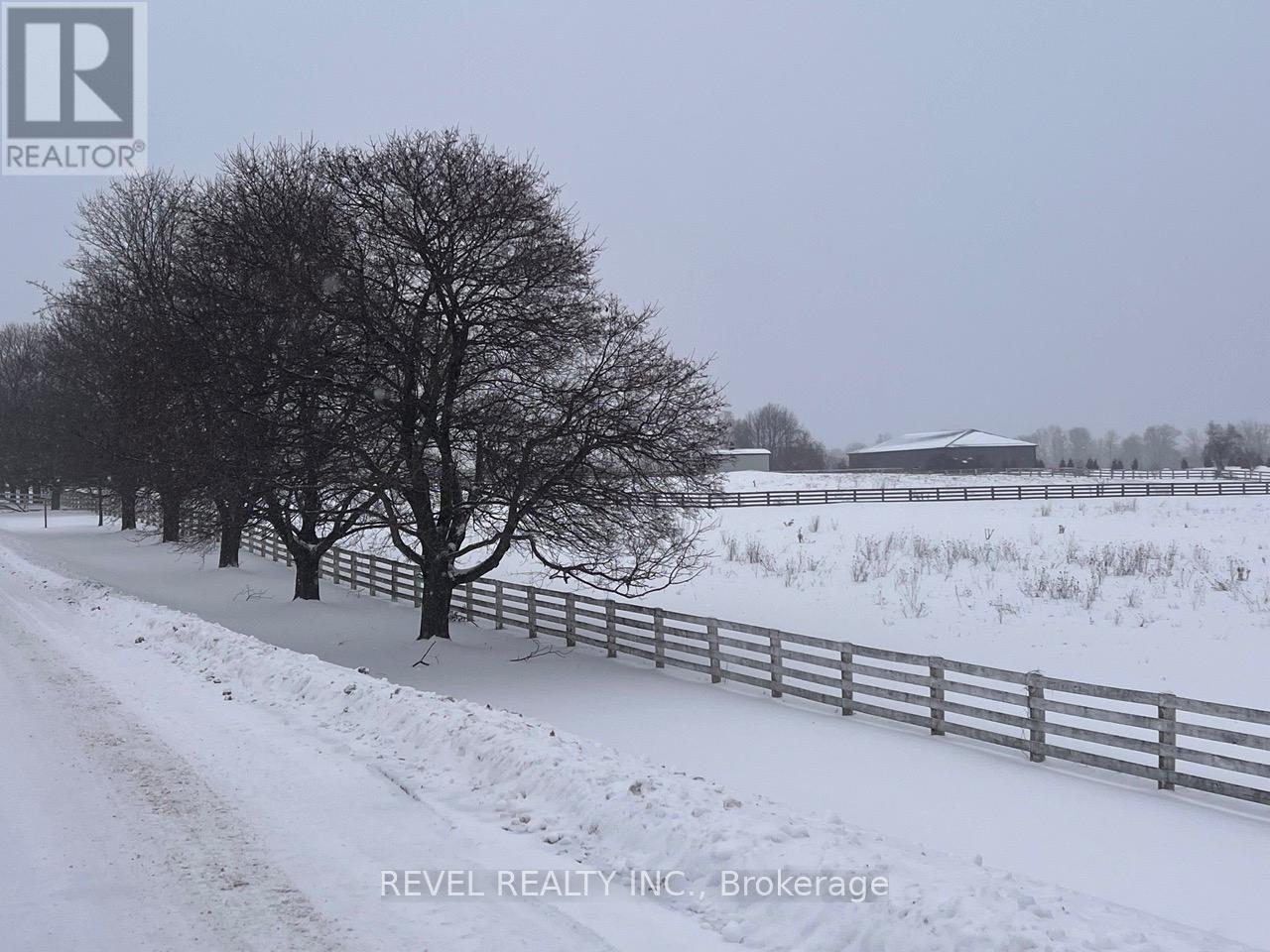 A snowy landscape with a fence and a tree.