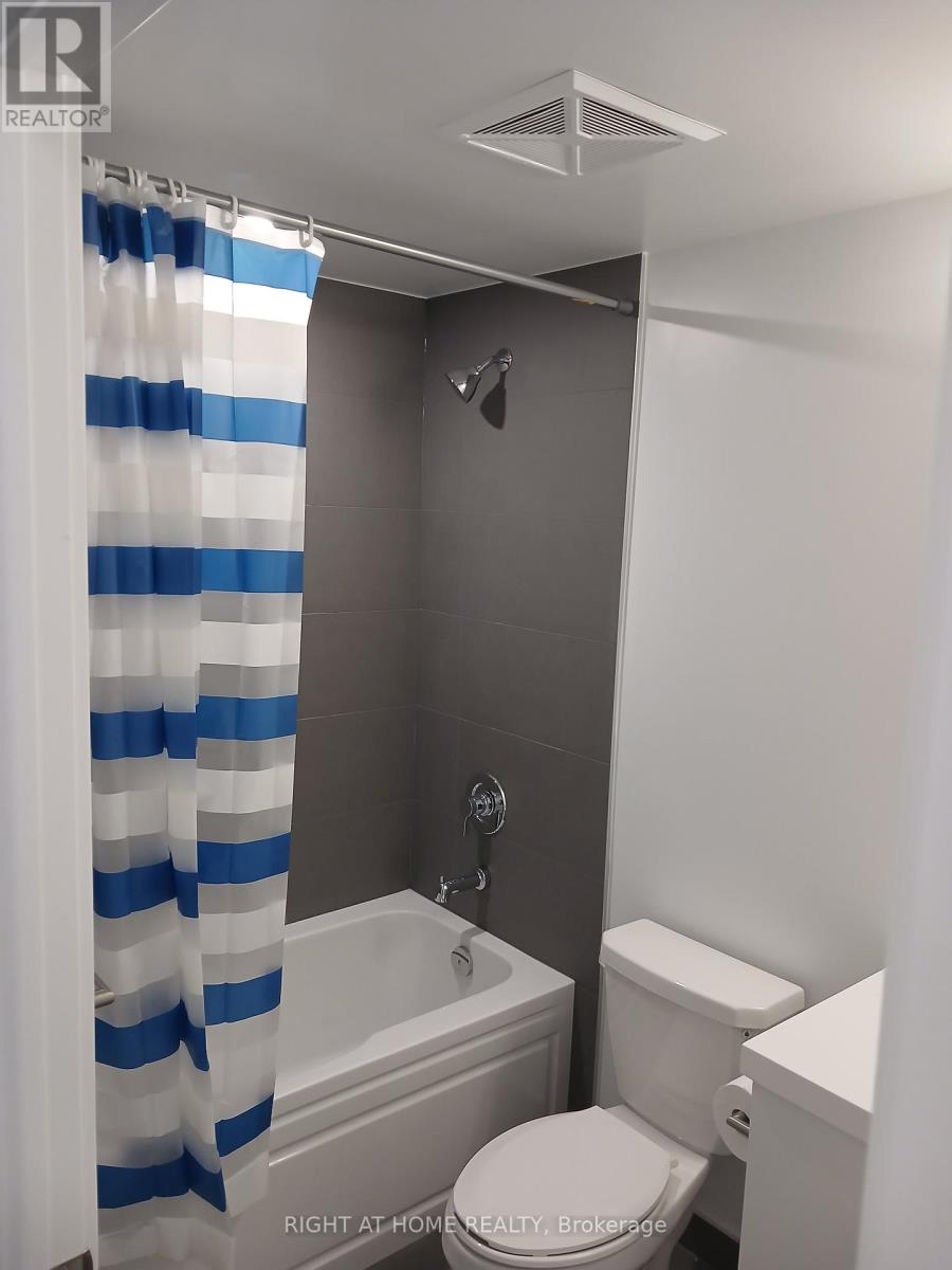 A white toilet sits next to a bathtub in a bathroom.