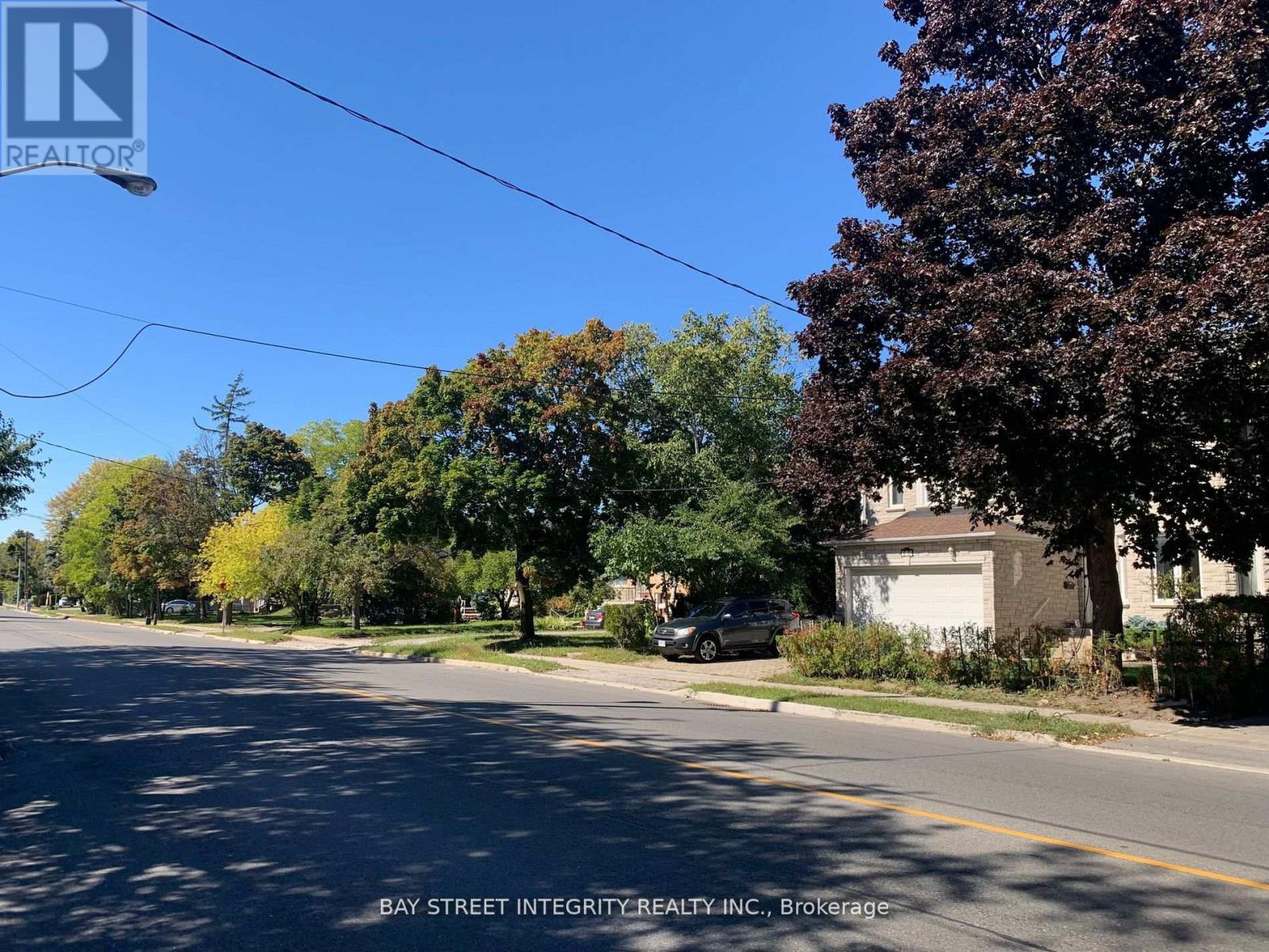A street with a car parked on the side and a house with a garage.