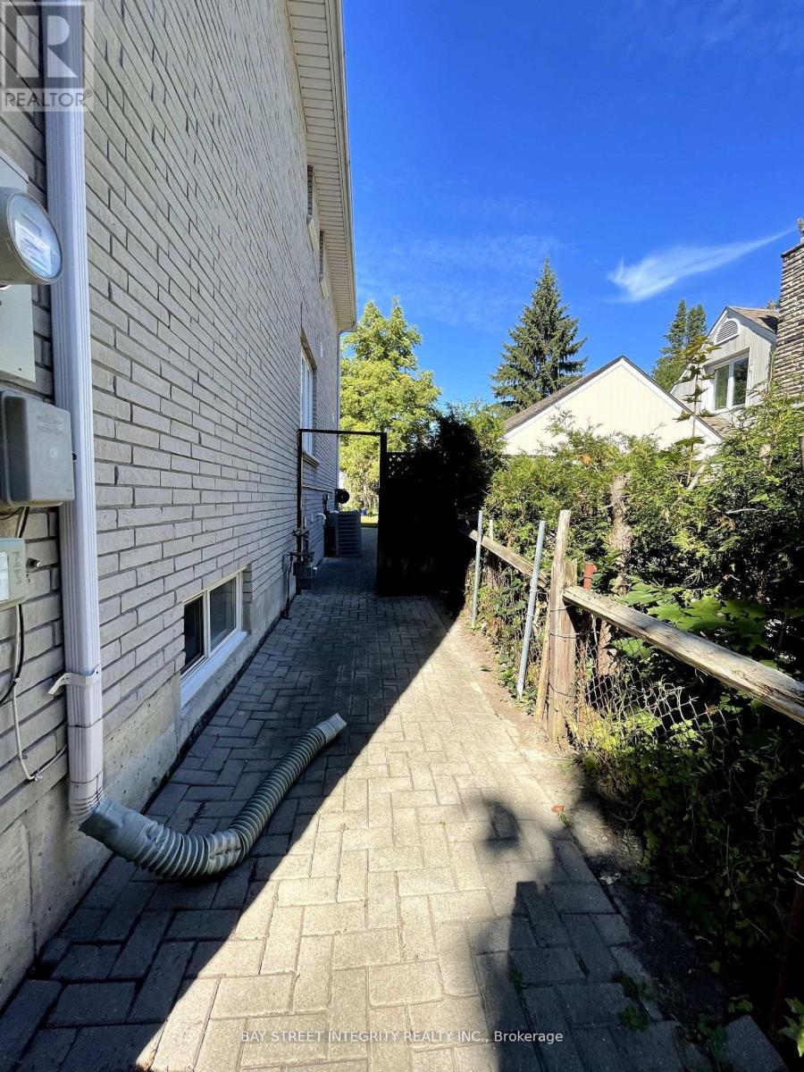 A narrow alley with a building on the left and a tree on the right.