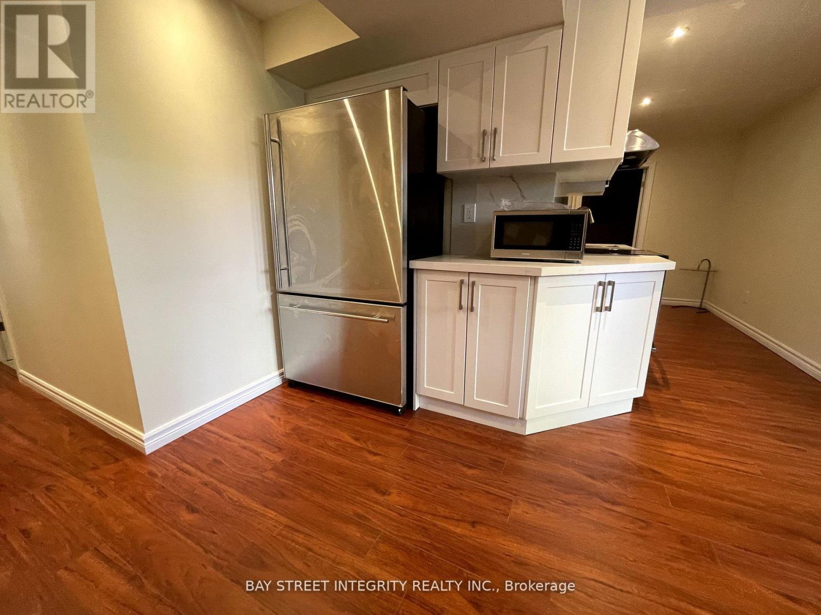 A kitchen with white cabinets and a stainless steel refrigerator.