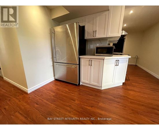 A kitchen with white cabinets and a stainless steel refrigerator.