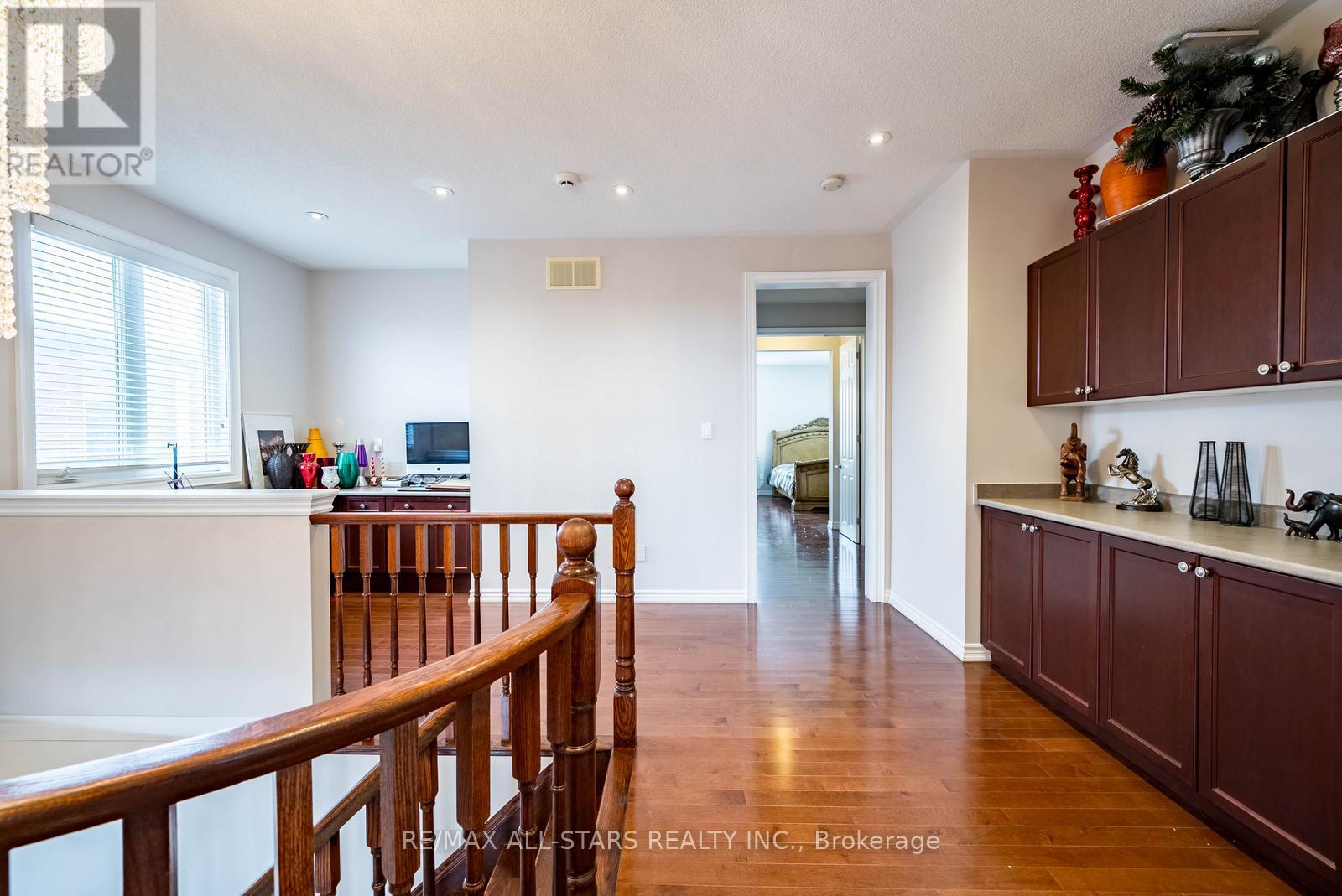 A well-lit, spacious room with wooden floors and furnished with a TV, a desk, and a chair.
