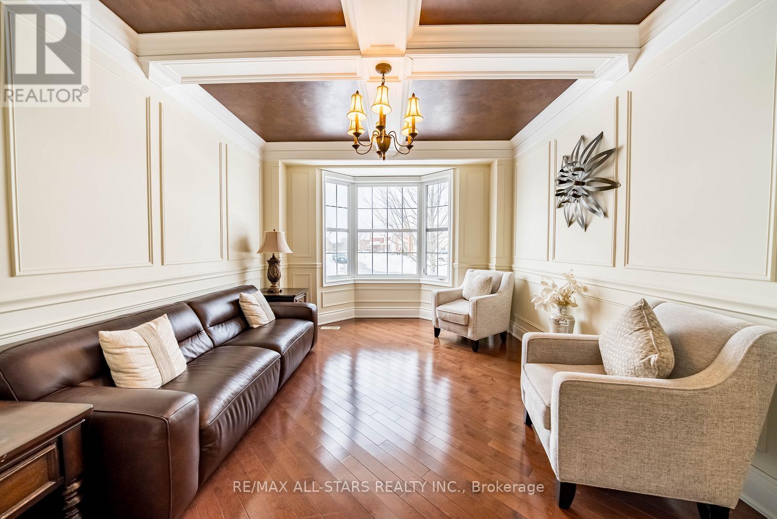 A living room with a brown leather couch and a chandelier.