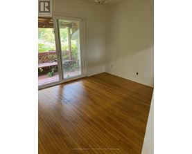 A room with wooden flooring and a door leading outside.