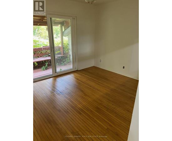 A room with wooden flooring and a door leading outside.