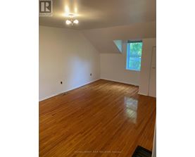 A room with wooden flooring and a window letting in natural light.