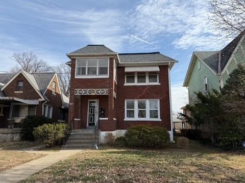 A red brick house with a white door and windows.