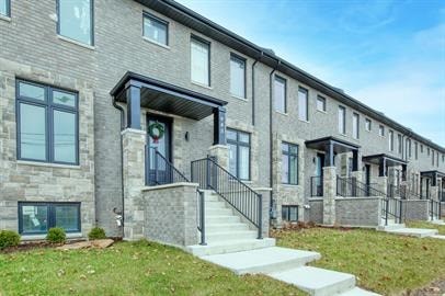 A row of modern houses with a front yard and a wreath on the door.