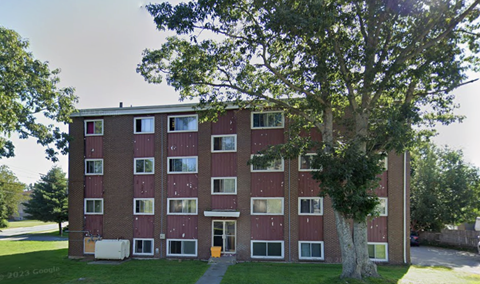 A red brick building with a tree in front.