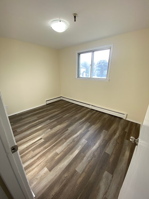 A room with a window and wooden flooring.