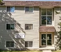 A grey building with a brown roof and a sign on the front.