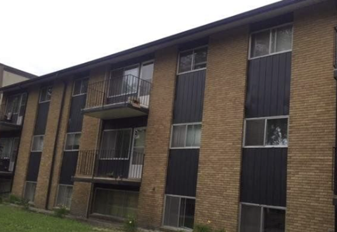 A brick apartment building with balconies and windows.
