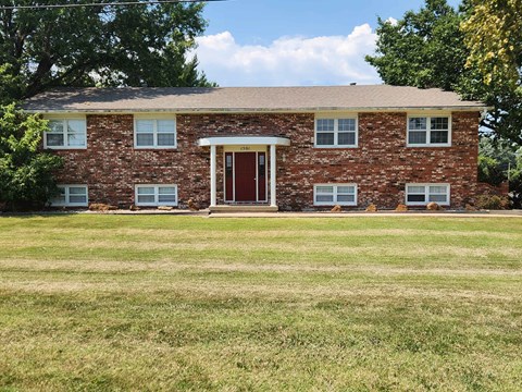 A brick house with a brown door and windows.