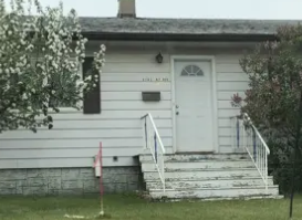 A small white house with a front porch and a mailbox.
