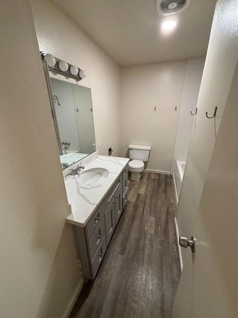 A bathroom with a sink, toilet and mirror.