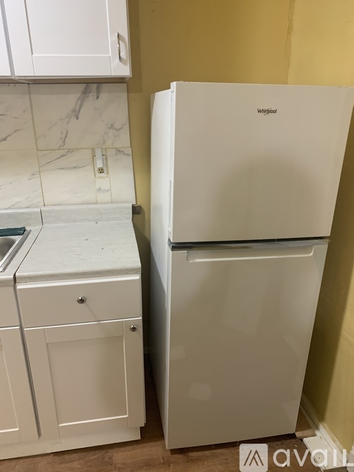A white Magnum refrigerator stands next to a white kitchen cabinet.