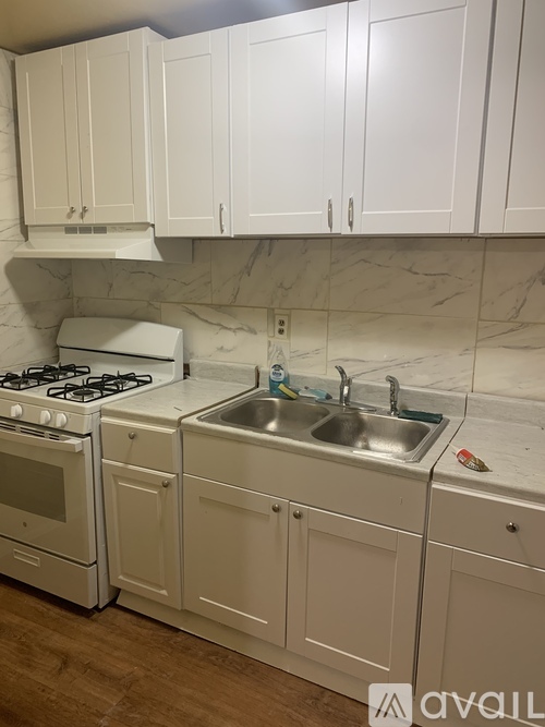 A kitchen with white cabinets and a marble backsplash.
