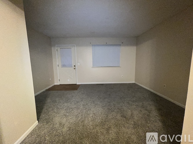 A room with a carpeted floor and two doors.