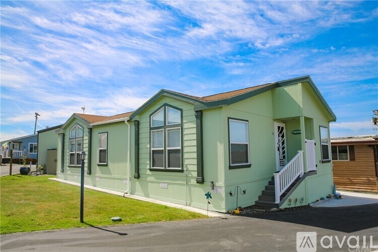 A green house with a white porch and a sign that says "available".