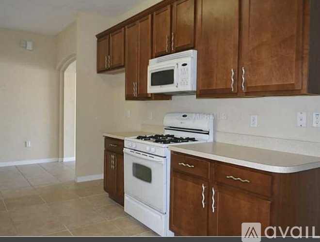 A kitchen with white appliances and brown cabinets.