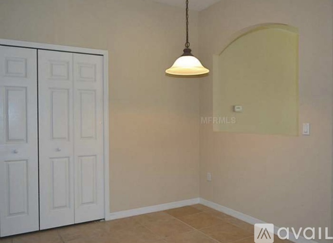 A room with a white door and a hanging light fixture.
