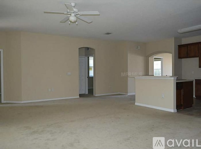 A spacious living room with a ceiling fan and a cabinet.