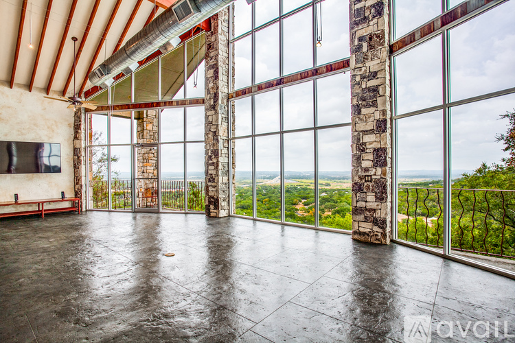 A large room with a stone pillar and a glass wall overlooking a green landscape.