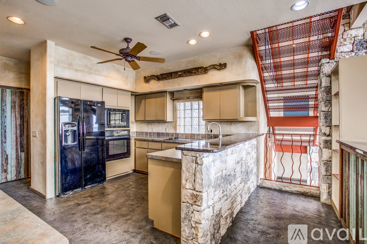 A kitchen with a black fridge and a ceiling fan.