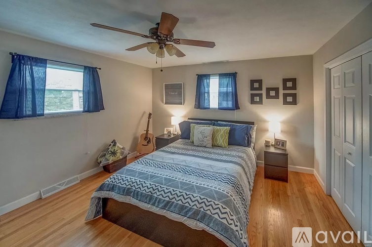 A bedroom with a bed, a ceiling fan, and a guitar on the wall.