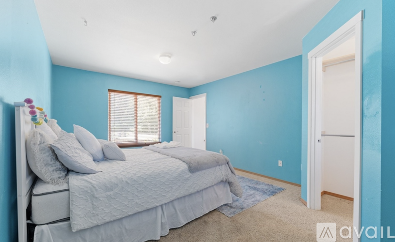 A bedroom with a bed, pillows, and a window.