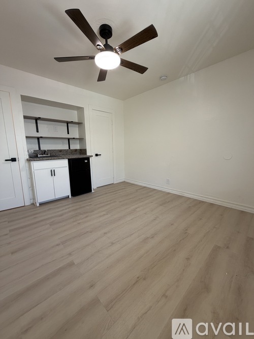 A room with a ceiling fan and wooden flooring.