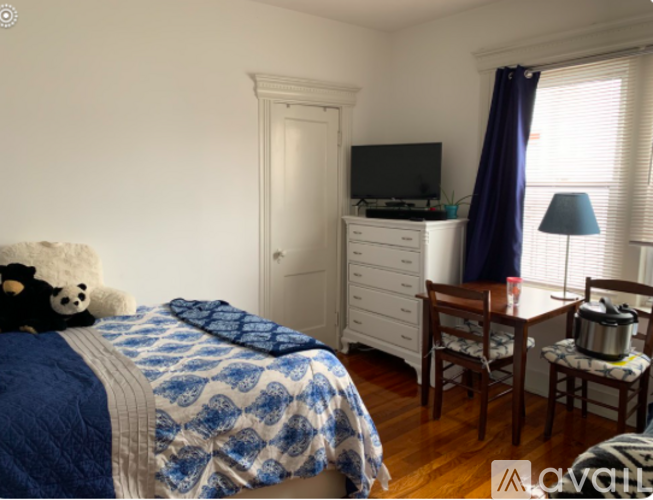 A bedroom with a bed, a chair, a dresser, and a window.
