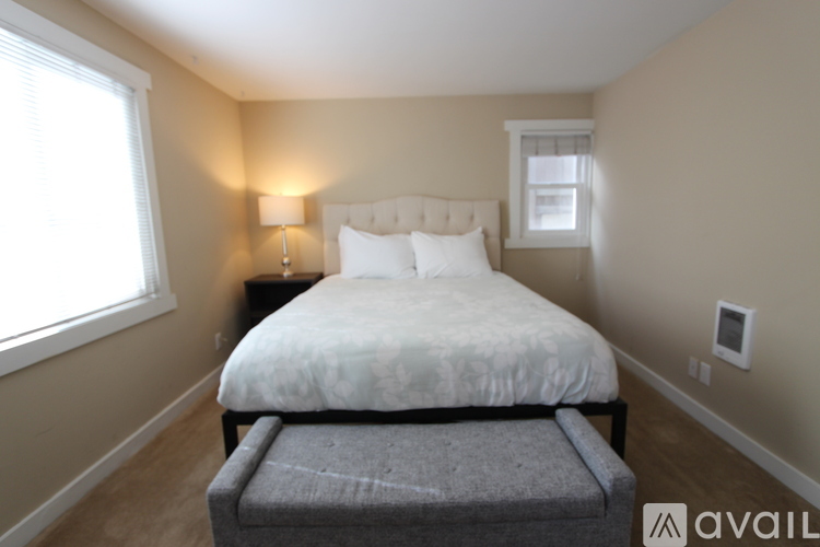 A bedroom with a bed, nightstand, and window.
