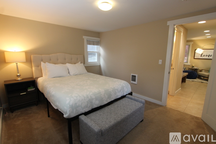 A bedroom with a large bed and a nightstand with a lamp.