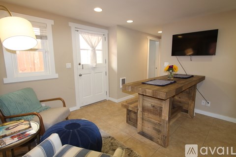 A living room with a wooden table and a flat screen TV mounted on the wall.