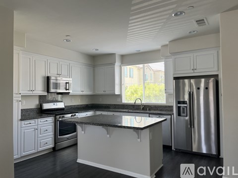 A kitchen with white cabinets and a black countertop.