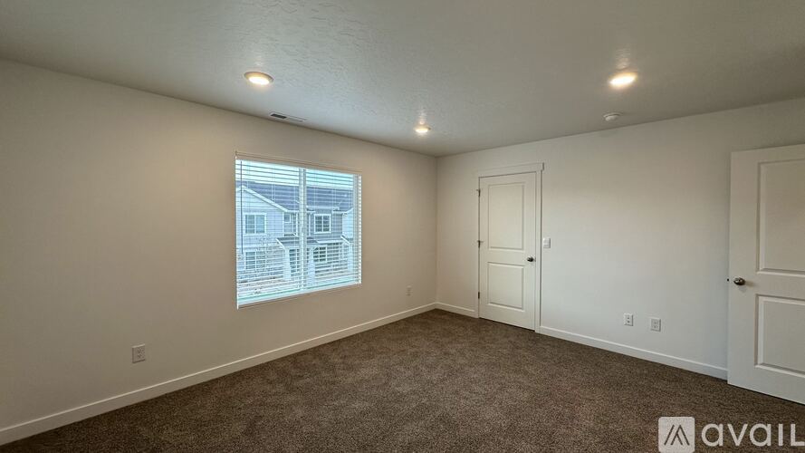 A room with a window showing a building outside, carpet on the floor, and a sign on the wall that says "available".