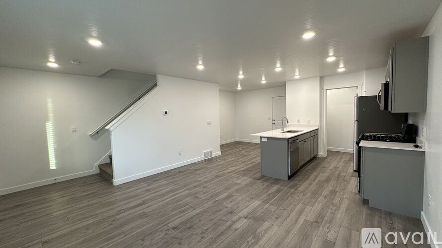 A spacious room with wooden flooring and a staircase leading to the upper level.
