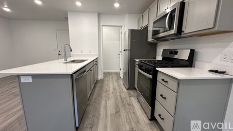 A kitchen with a white counter top and stainless steel appliances.