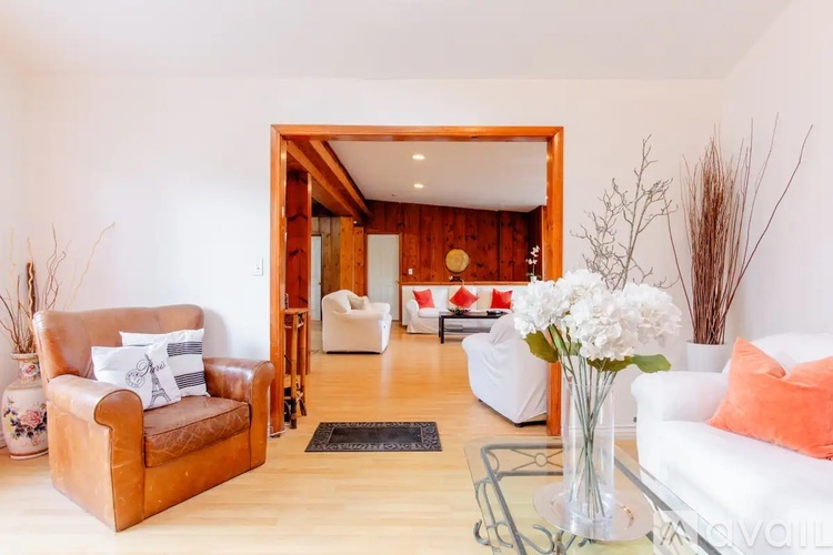A living room with a brown leather chair and a white couch.