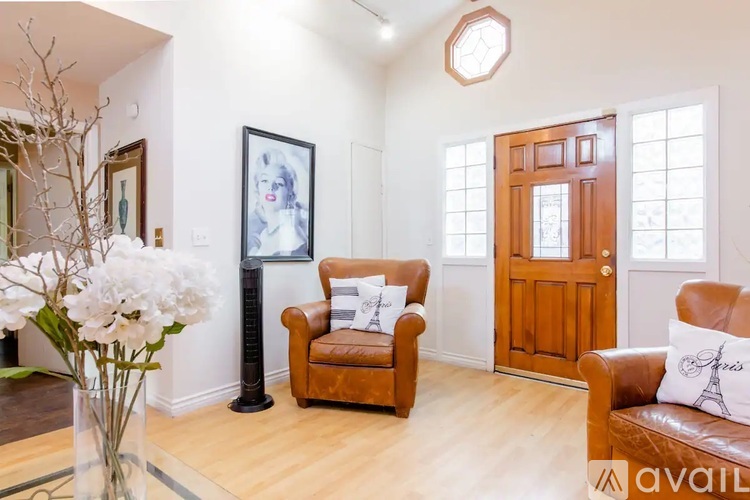A living room with a brown leather couch, a brown armchair, and a wooden door.