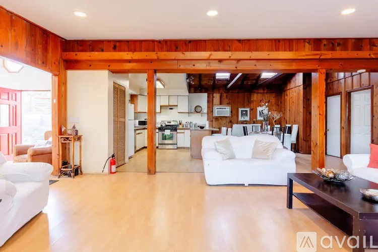 A spacious living room with a kitchen in the background.