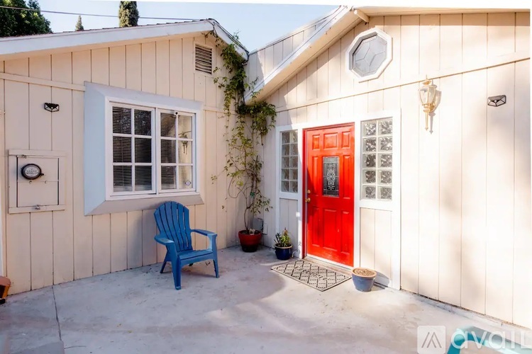 A red door is on the right side of a white house.
