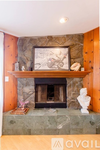 A stone fireplace with a picture frame above it and a statue on the mantle.