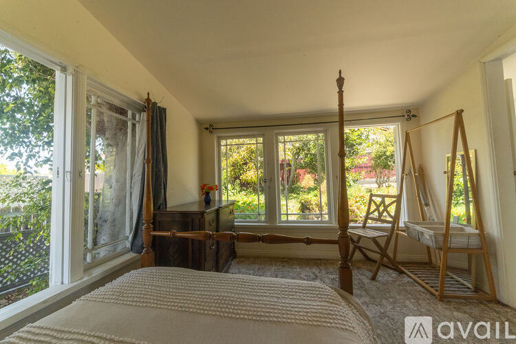A bedroom with a large bed and a window overlooking a garden.