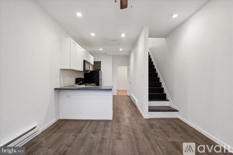 A spacious, well-lit kitchen and living room with a staircase leading to the upper floor.